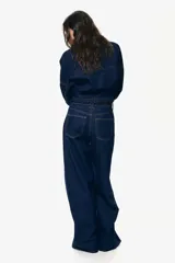 Pantalón de jean azul oscuro de tiro alto, corte recto y pierna ancha. Diseño de cinco bolsillos con costuras a la vista. Inspirado en los años 70.