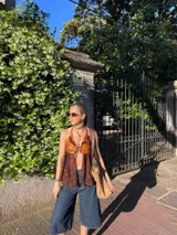 Top halter marrón con detalles de cuero y tela bordada, con tiras ajustables en cuello y espalda.