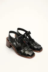 Sandalias plateadas de cuero con tiras entrecruzadas y hebilla lateral. Taco de madera de 6 cm.