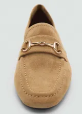 Mocasín de cuero color camel con punta fina y detalle de hebilla metálica dorada.