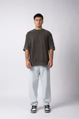 Remera oversize de algodón pesado, color gris oscuro con efecto lavado 'snow' que le da un aspecto gastado y único. Presenta cuello redondo y costuras vistas en hombros y mangas.