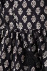 Vestido corto evasé de algodón liviano, color negro con estampado floral en tonos beige. Tiene cuello mao, abertura en V con tiras finas con borlas, mangas globo largas con elástico en los puños y cintura fruncida.