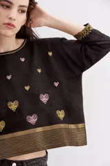 Camisa negra de viscosa con jacquard de lurex, calce amplio y escote redondo. Presenta bordados de corazones dorados y rosados, y guardas doradas en el ruedo y los puños.