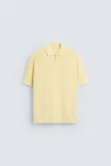 Polo color amarillo claro de punto con cuello solapa y cierre frontal con cremallera.