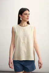 Blusa color crema sin mangas, de lino, con cuello redondo y corte recto.