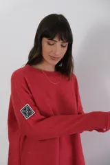 Buzo azul de viscosa con cuello redondo y manga larga. Presenta un aplique con diseño geométrico en el brazo izquierdo.