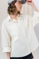 Camisa color crema de algodón liviano, calce oversize, con cuello camisero, cierre abotonado, mangas largas con opción de arremangado y dos bolsillos frontales con solapa.
