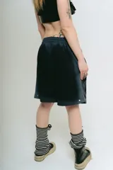 Bermuda de felpa negra con efecto lavado (washed) que aclara hacia los laterales. Presenta un gran estampado serigrafiado en blanco con motivos florales y caracteres orientales estilizados. Posee cordón de ajuste en la cintura y remaches metálicos cromados en los laterales.