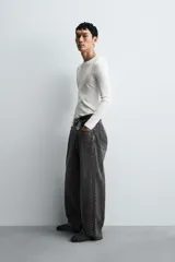 Pantalón de jeans de algodón, corte baggy fit, tiro medio, con efecto lavado en tonos grises y verdes. Presenta cinco bolsillos y cierre frontal con cremallera y botón.