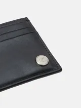 Tarjetero de piel negro, diseño compacto con múltiples ranuras para tarjetas y placa metálica circular con el monograma de Calvin Klein en la parte frontal.