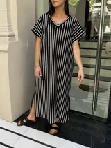 Vestido largo de tejido a rayas horizontales en tonos beige y blanco, con escote en V y mangas cortas tipo murciélago. Presenta tajos laterales en el ruedo.