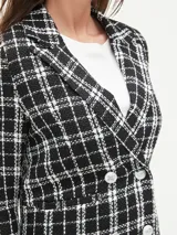 Blazer negro con estampado a cuadros blancos, doble botonadura y solapas de muesca.
