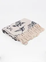 Alfombra rectangular color crema con estampado floral en azul y flecos en los bordes.