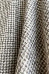 Poncho color beige con diseño a cuadros, cuello bote y terminaciones desflecadas. Tiene aberturas para los brazos en los laterales y detalles en cuero.