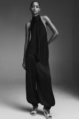 Top sin mangas color blanco, con cuello halter drapeado y bajo asimétrico con caída.