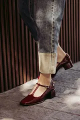 Zapatos de charol negro con diseño tipo T-bar, taco bajo cuadrado y punta redondeada.