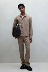 Pantalón de vestir color beige con textura de lino, corte recto, bolsillos laterales y traseros con botón. Cierre con cremallera y botón oculto.