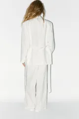 Blazer oversize color blanco confeccionado con 22% de lino. Tiene cuello solapa, manga larga con hombreras y abertura en la espalda. Incluye cinturón lazada en el mismo tejido.