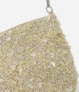 Cartera pequeña transversal color crema, cubierta de lentejuelas y cuentas. Tiene asa de cadena plateada y cierre de cremallera.