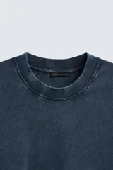 Camiseta azul marino de corte holgado, confeccionada en algodón con cuello redondo y mangas cortas. Presenta un efecto de lavado que le da una apariencia única.