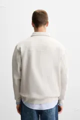 Sudadera negra de cuello alto con cierre frontal de cremallera, corte relaxed fit, manga larga y terminaciones en rib.