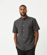 Camisa de hombre de corte clásico, color gris oscuro con estampado de cuadros blancos, cuello abotonado, manga corta y cierre frontal con botones blancos.