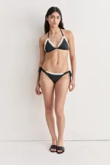 Conjunto de bikini negro con detalles de crochet blanco en los bordes. El corpiño es de corte triangular y la bombacha es regulable con lazos laterales.