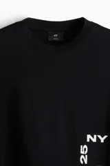 Remera negra de corte holgado con estampado blanco en el frente que incluye las letras "NY" y el número "25".