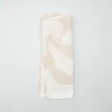 Bufanda grande color beige con diseño abstracto y borde con flecos, ideal para abrigarse.
