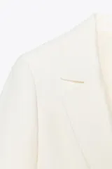 Blazer fucsia de cuello solapa y manga larga con hombreras. Detalle de tejido efecto arrugado. Bolsillos delanteros de vivo. Cierre frontal con un botón.