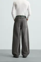 Pantalón de jean gris de corte amplio, estilo balloon fit, con cinco bolsillos, cierre frontal con cremallera y botón, y efecto de color lavado en toda la prenda.