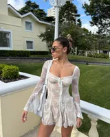 Minivestido color nude con encaje floral blanco, escote corazón con lazo ajustable, mangas largas acampanadas de encaje y corte ajustado al cuerpo.