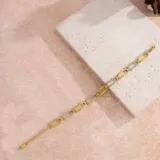Pulsera dorada con eslabones rectangulares alternados, algunos con incrustaciones de circonitas blancas.