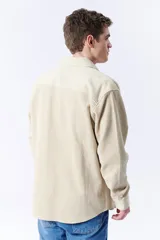 Sobrecamisa beige de pana con cuello clásico, cierre frontal con botones, mangas largas con puños abotonados y dos bolsillos de parche en el pecho.