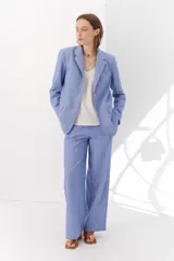 Blazer de lino color crudo con rayas verticales finas en color dorado, de corte recto, con solapas y cierre con un botón.