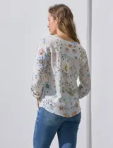 Blusa de gasa estampada con rayas verticales en tonos naranja, amarillo y blanco. Tiene cuello a la base, escote en V y botones. Delantera con bolsillo aplicado. Largo de manga regulable con presilla y botón. Terminación anudada opcional.