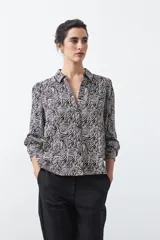 Camisa de manga larga color marrón con estampado de lunares blancos, confeccionada en tejido liviano con cuello clásico y botones frontales.