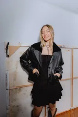 Campera bomber negra de cuero con cuello de piel sintética, forro interior y detalles de pasamanería en cuero marrón gastado.