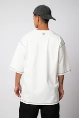 Remera negra oversize con mangas cortas y costuras a la vista en color blanco.
