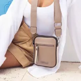 Phonebag color mostaza con bolsillo frontal con cierre, espacio para celular y billetera con repartición. Tiene una correa gruesa de galón regulable y desmontable. Detalles en marrón y beige.