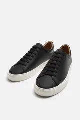 Zapatillas blancas de cuero sintético con cordones, forro interior y plantilla color beige.