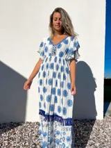 Vestido largo blanco con estampado floral azul, escote en V con bordado y mangas cortas con volados.