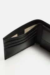 Billetera de cuero negra con costuras al tono. Cuenta con compartimento para billetes, tres compartimentos para tarjetas y un monedero con cierre mediante clip.