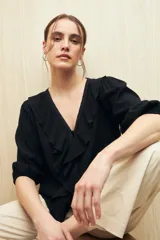 Blusa negra con mangas 3/4 y escote en V con volados.