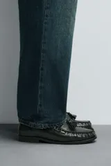 Mocasín de vestir de cuero color verde oscuro, con borlas decorativas en el empeine, punta redondeada y suela con ligero tacón.