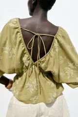 Top amarillo con estampado floral en jacquard, escote en pico, mangas cortas abullonadas con elástico, cintura elástica y espalda descubierta ajustable con lazos.