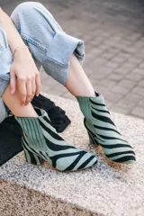 Botines de cuero con estampado de cebra en tonos verde claro y negro, con puntera fina y tacón cuadrado. Presentan paneles laterales elásticos en color verde liso.