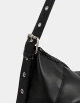 Cartera hobo color marrón claro de cuerina con correa regulable y hebilla decorativa frontal.