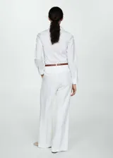Camisa blanca entallada de popelina de algodón con cuello camisero, cierre frontal con botones y mangas largas con puños abotonados.