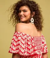Vestido corto de viscosa y lino con estampado de olas en color blanco sobre fondo rojo. Tiene escote off-shoulder, mangas cortas holgadas, lazo en el busto con detalle de abalorios y volado en el bajo.